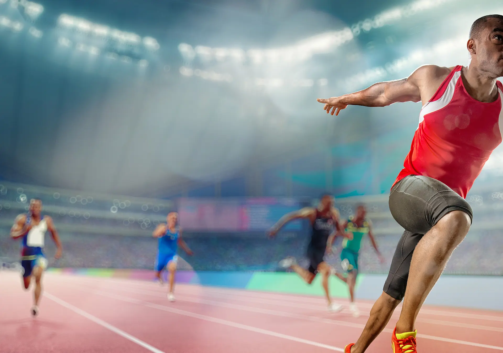 Male track athlete sprinting over the finish line of a race with his arms outstretched in victory