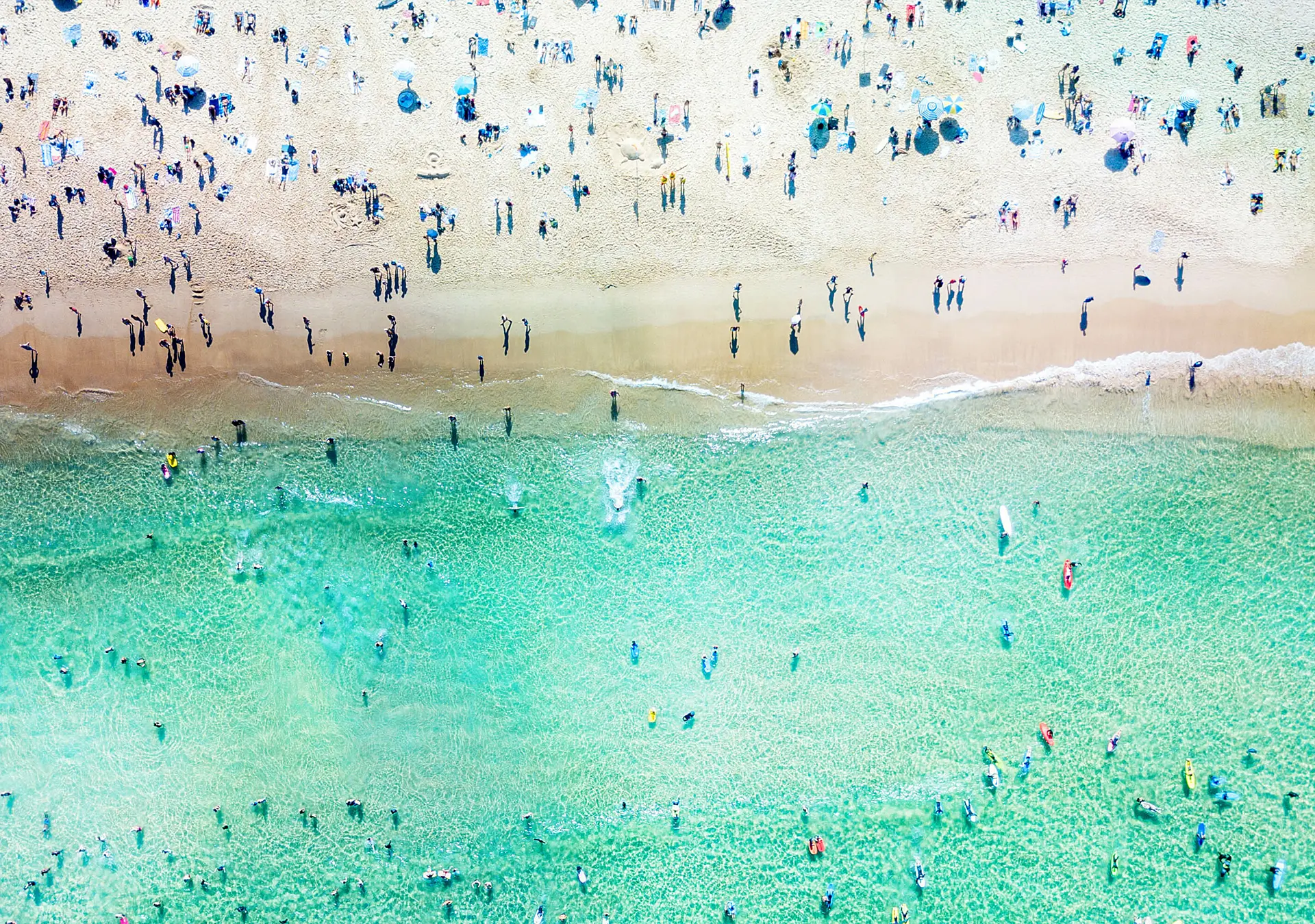 An aerial view looking down at Bondi Beach in Sydney on a busy day with blue water