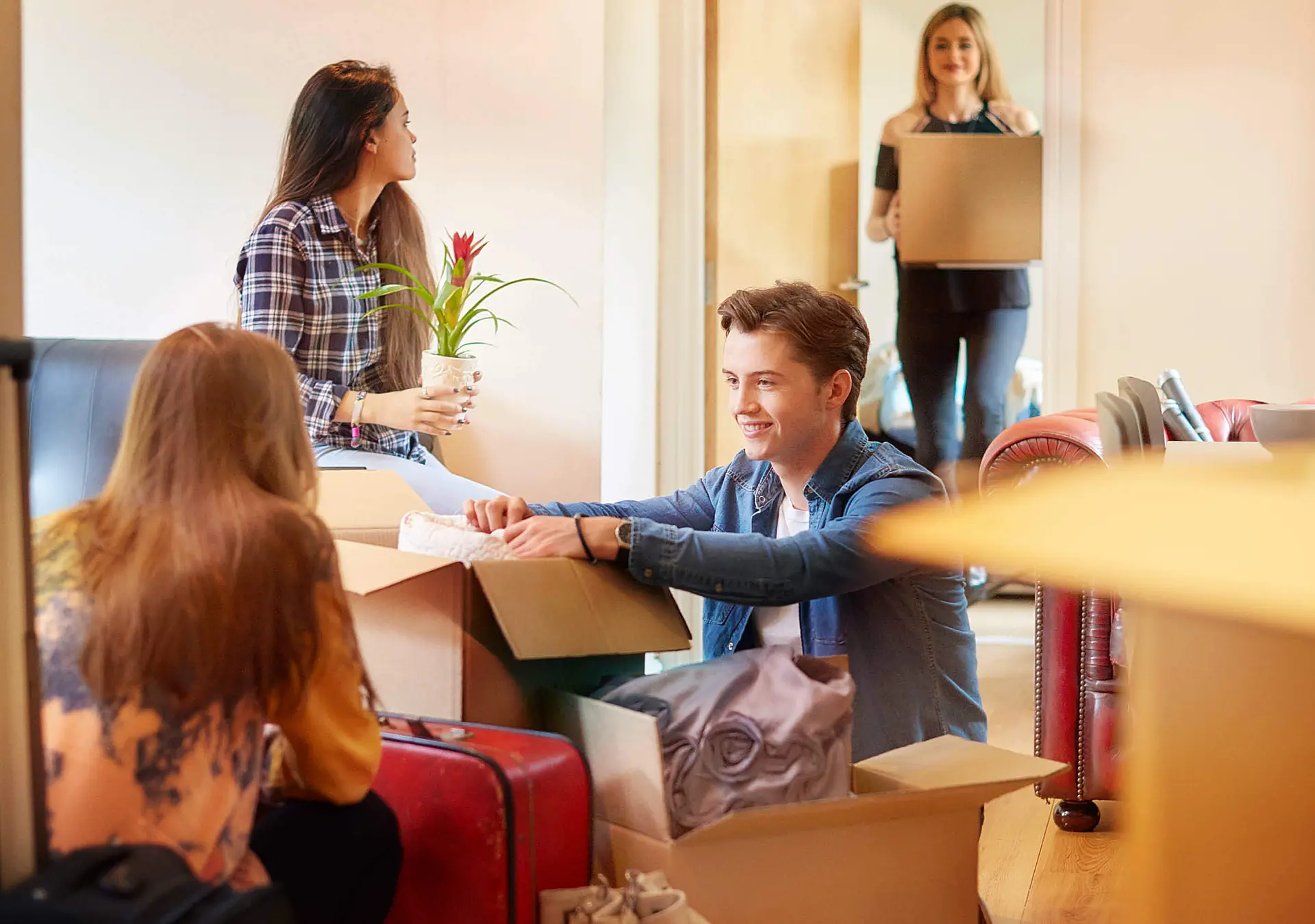 A group of four university students move into their shared flat/apartment, start to unpack boxes.