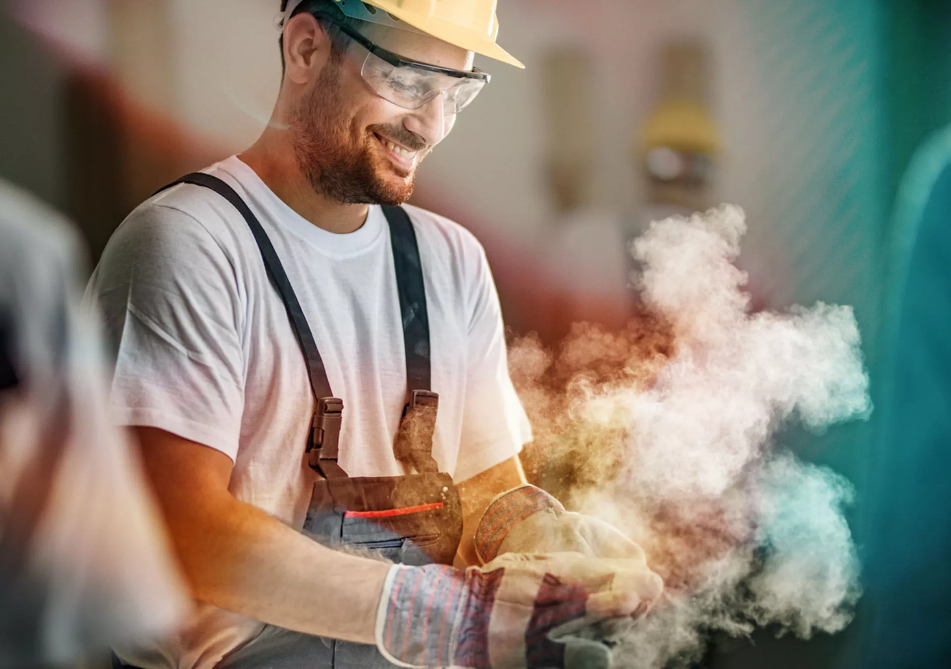 Smiling construction worker cleaning his gloves from sawdust at construction site.