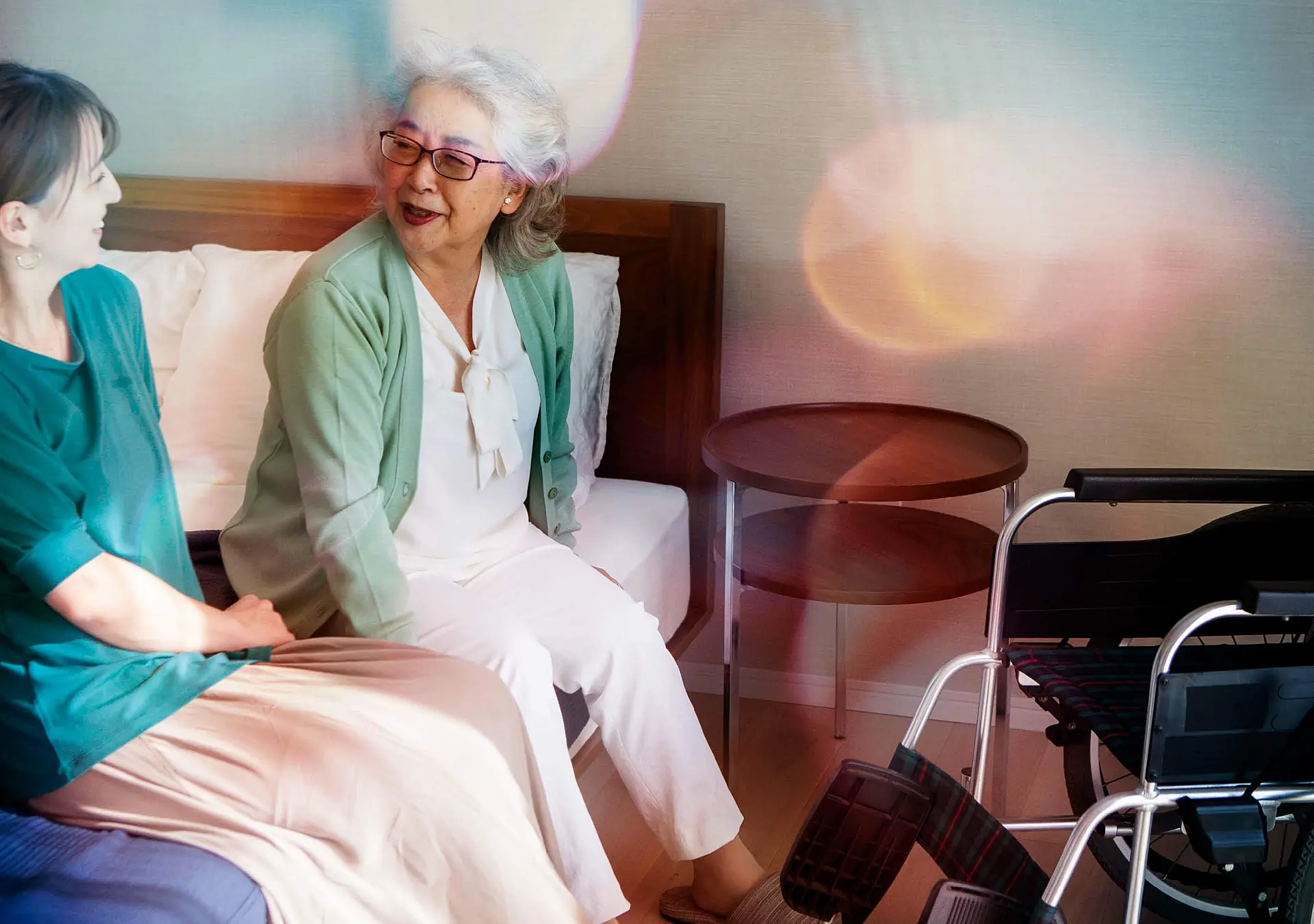 A senior woman happily chatting with her daughter on bed.