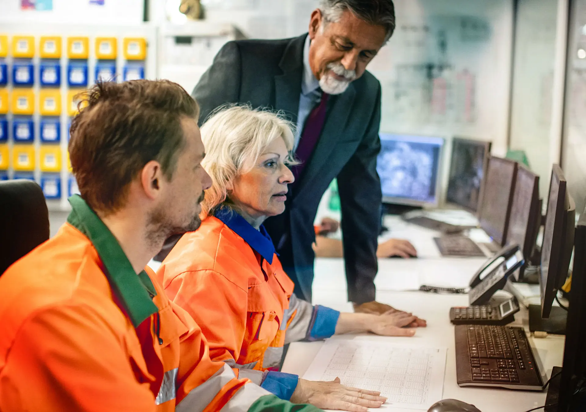 Side viewpoint of control room workers facility and senior manager observing their productivity.