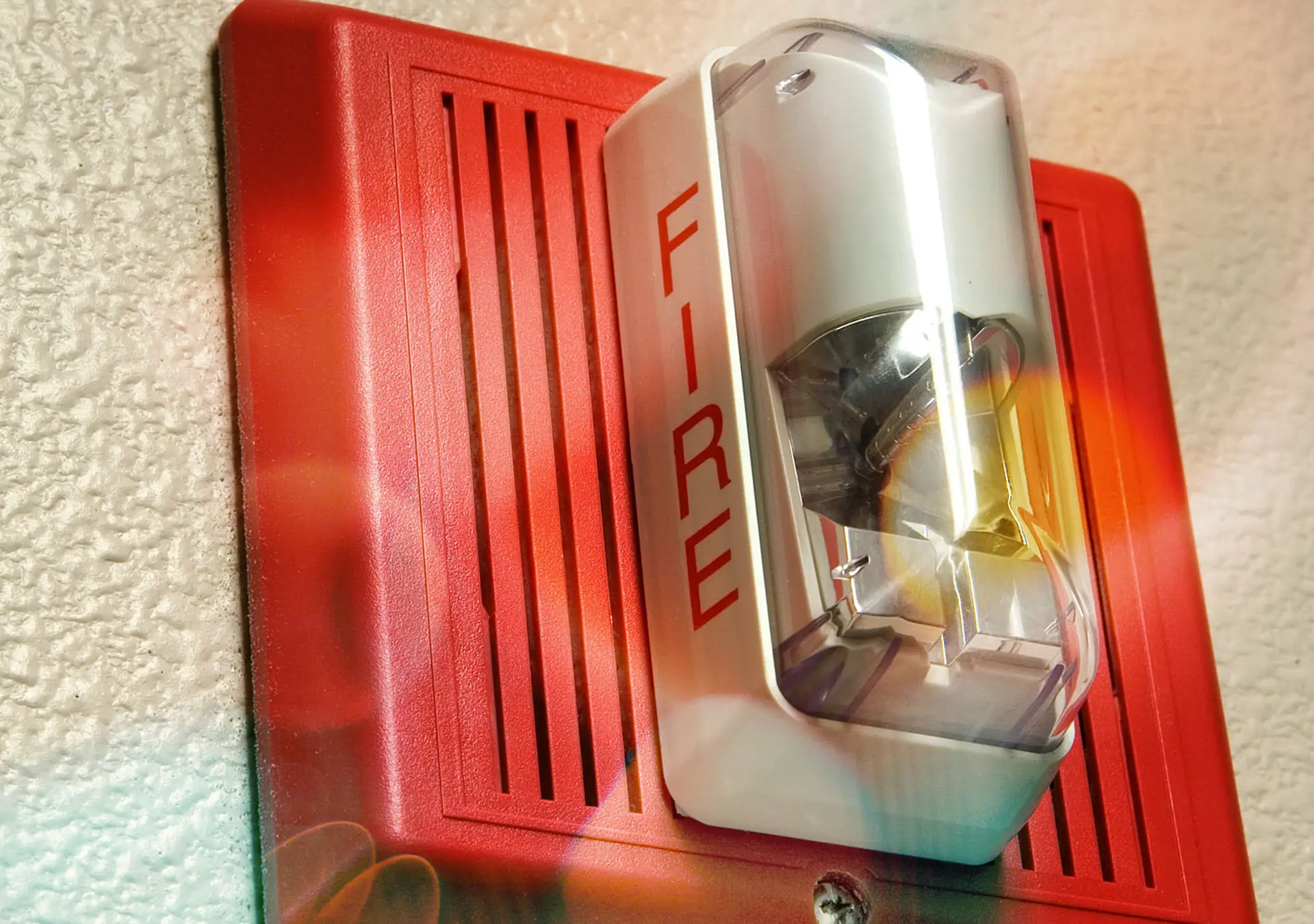 Fire alarm light and siren hanging on wall.