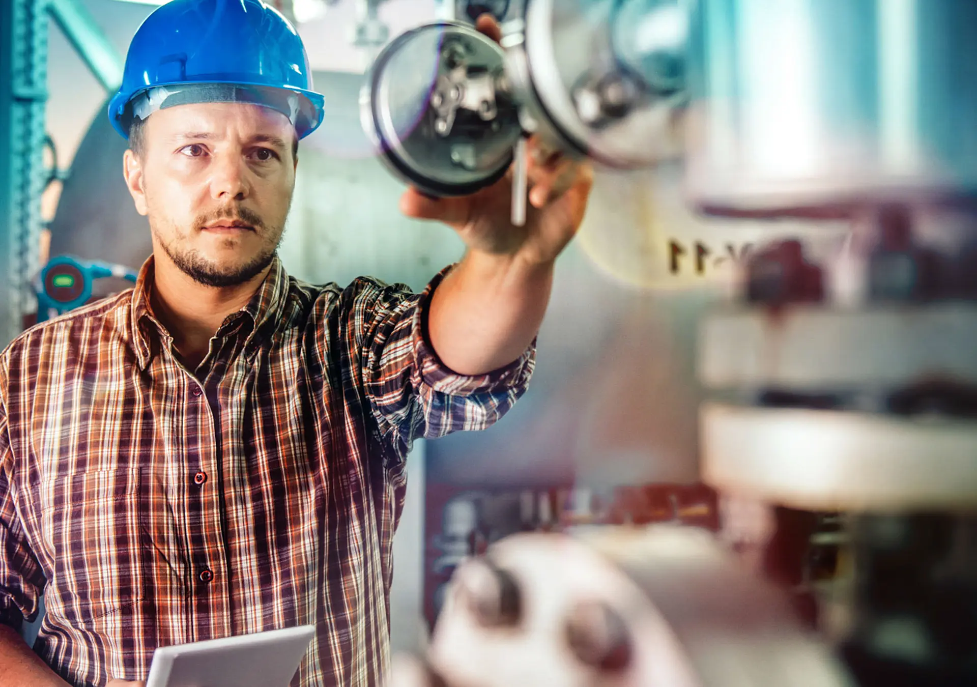 Man wearing blue hardhat using tablet at Natural gas processing facility