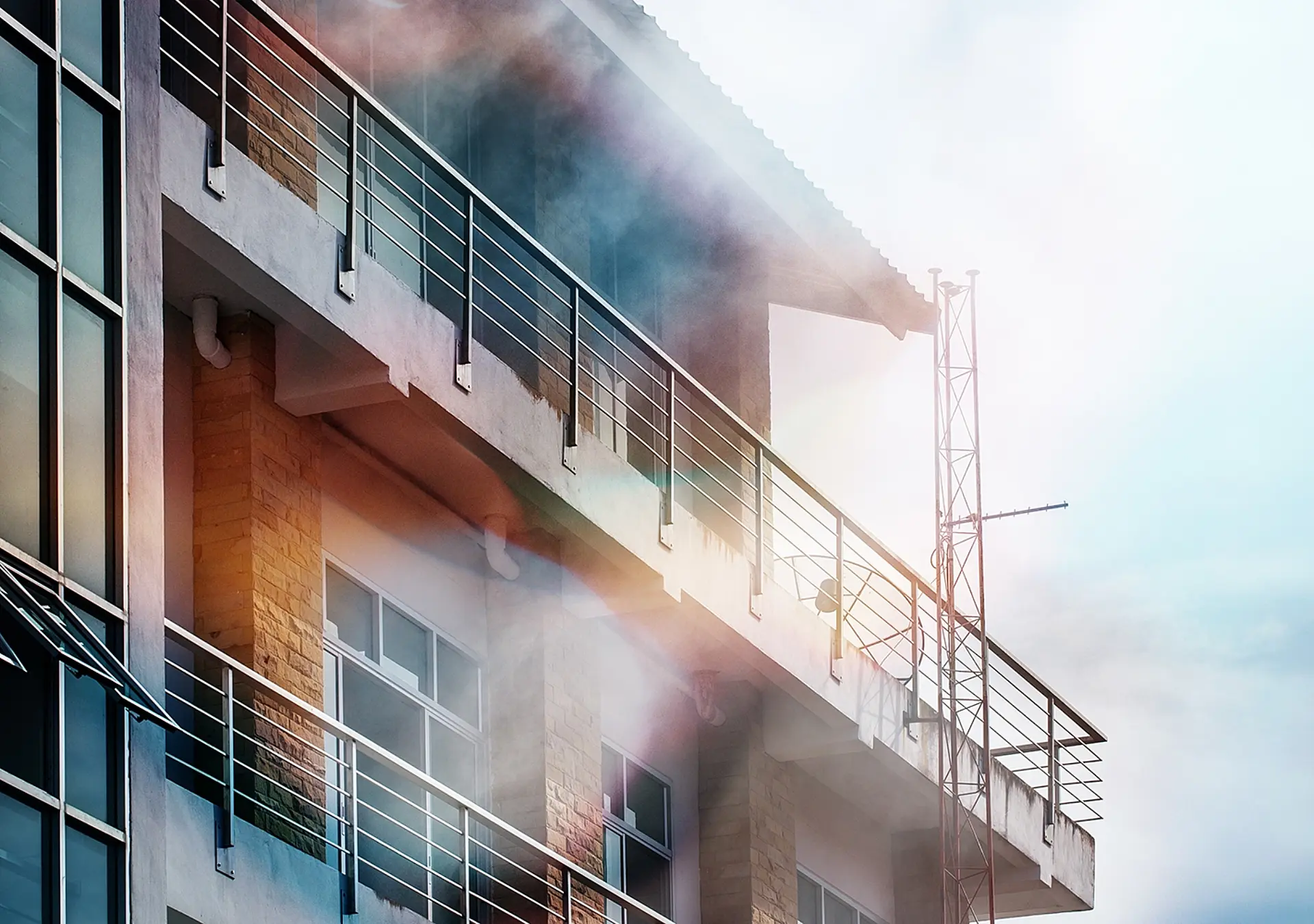 The smoke coming out of the front of the high building due to a fire.