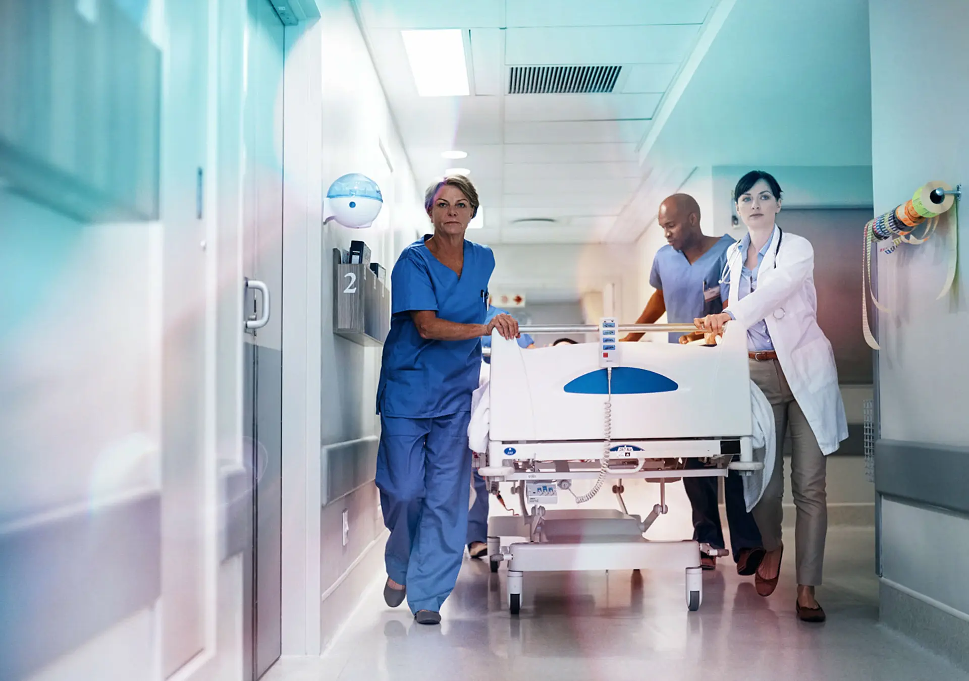 Full length shot of a medical team pushing a patient down the hallway in a gurney