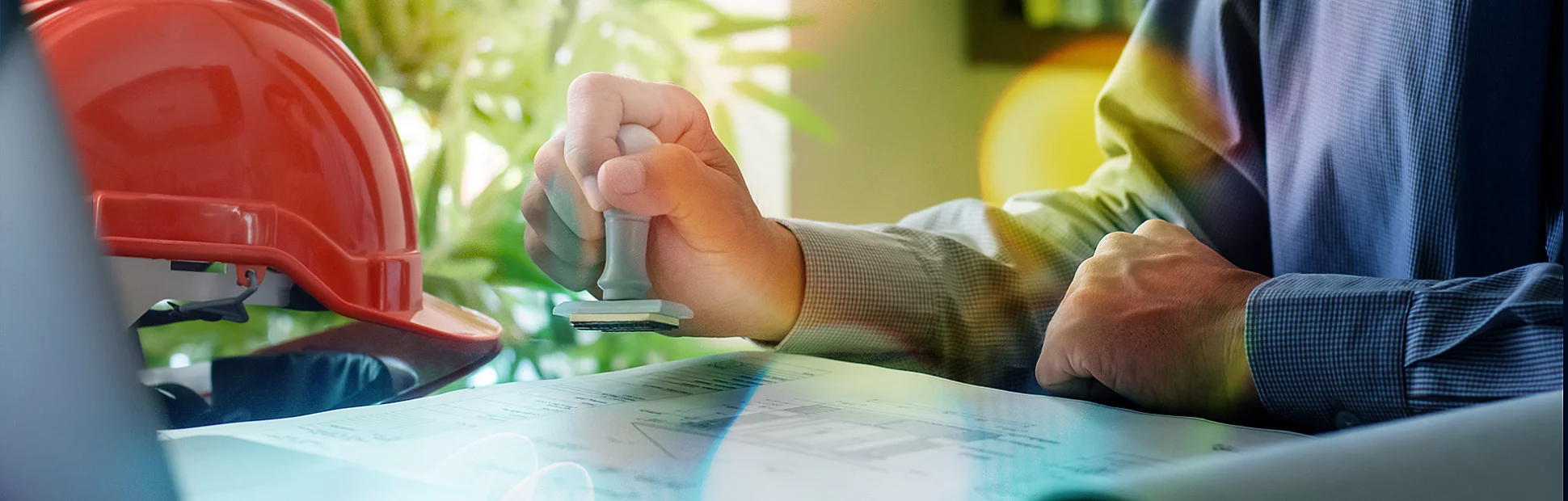 Male engineer hand stamping rubber stamper on blueprint paperwork at office. 