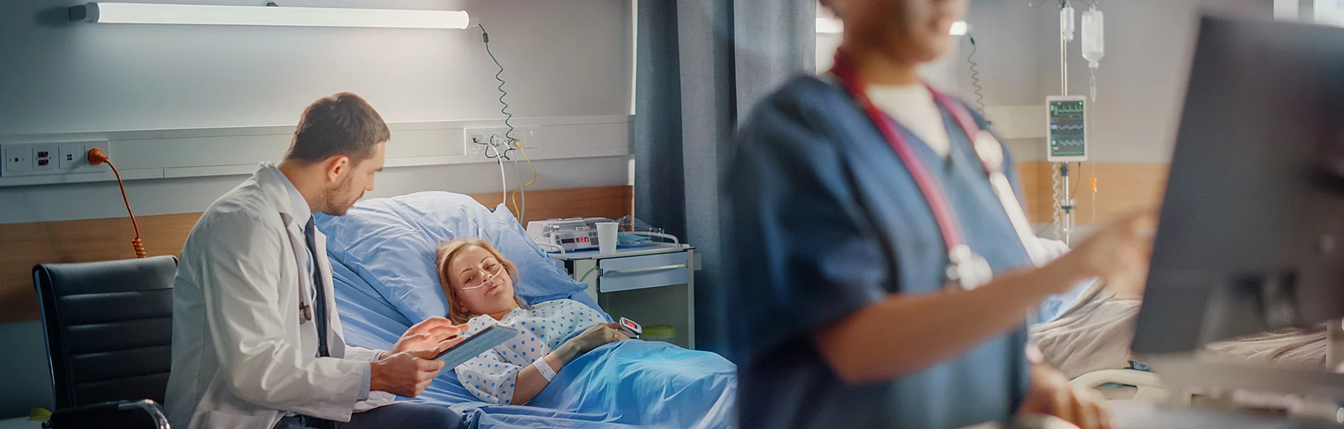 Female Head Nurse Uses Medical Computer, In the Background a Doctor is Consulting a Patient