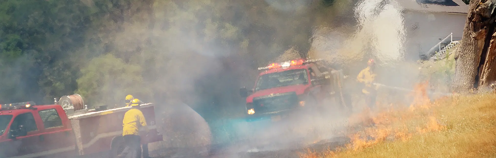 Firefighters working a natural cover fire in grass using brush truck apparatus