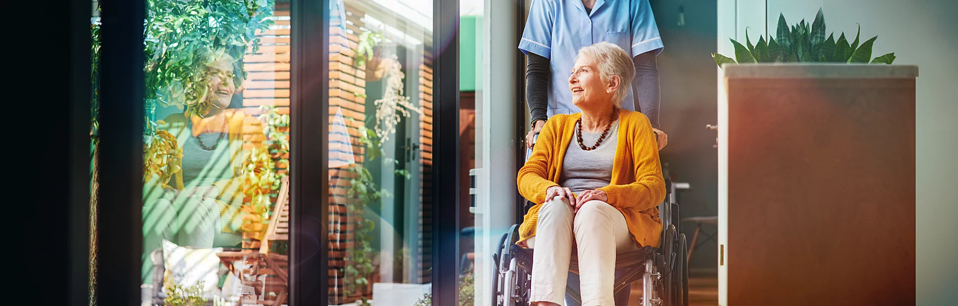 A young nurse pushing a senior woman in a wheelchair in a retirement home