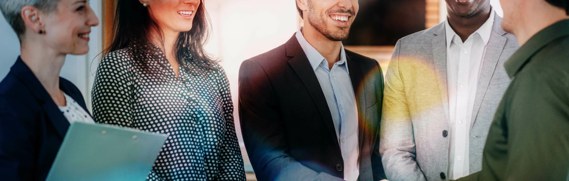 Group of business people in the office, two of them shaking hands, looking happy