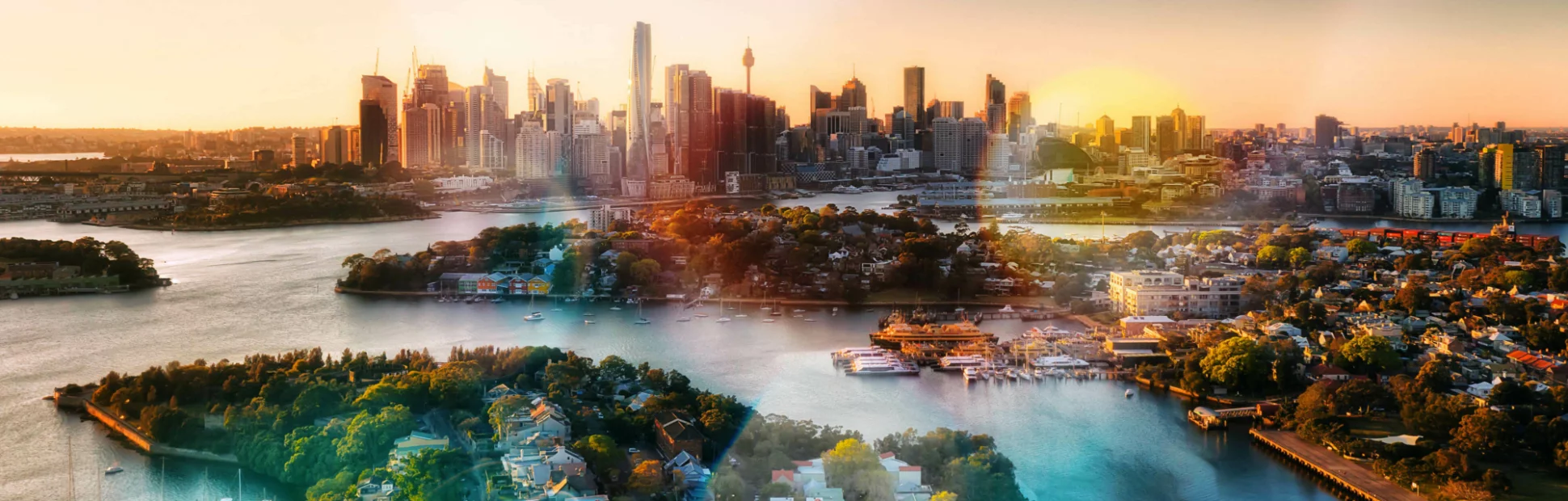Panoramic view looking at homes along a large river with tall city buildings in the background