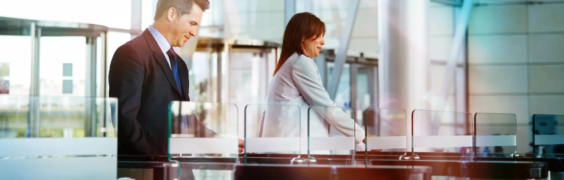 two businesspeople entering their workplace through security turnstiles