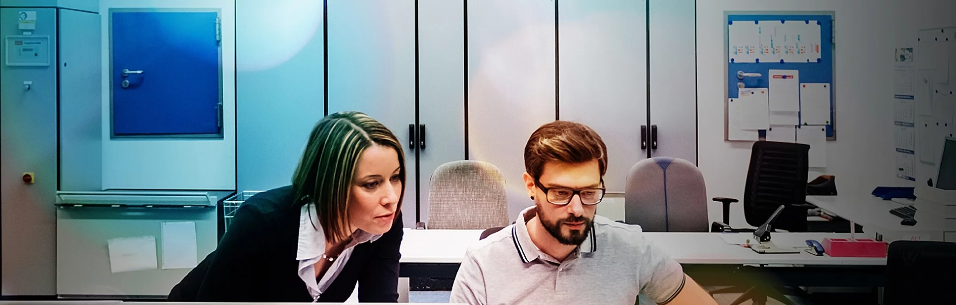 Two co workers looking at computer screens in the office