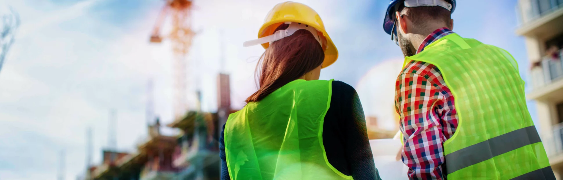 Two construction workers wearing protective gear discussing next steps