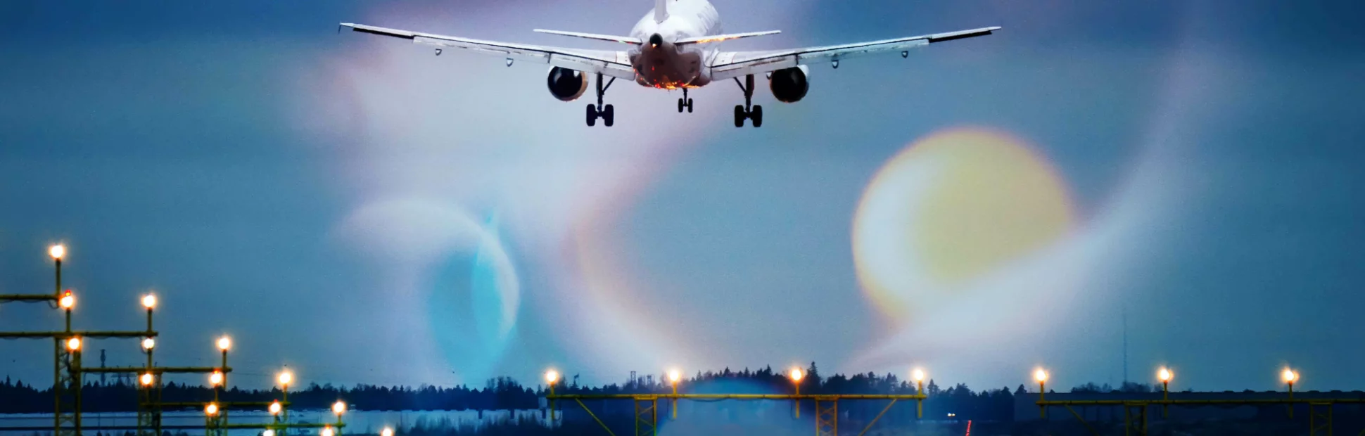 Commercial airliner lands to runway on foggy day, runway landing lights lit on.