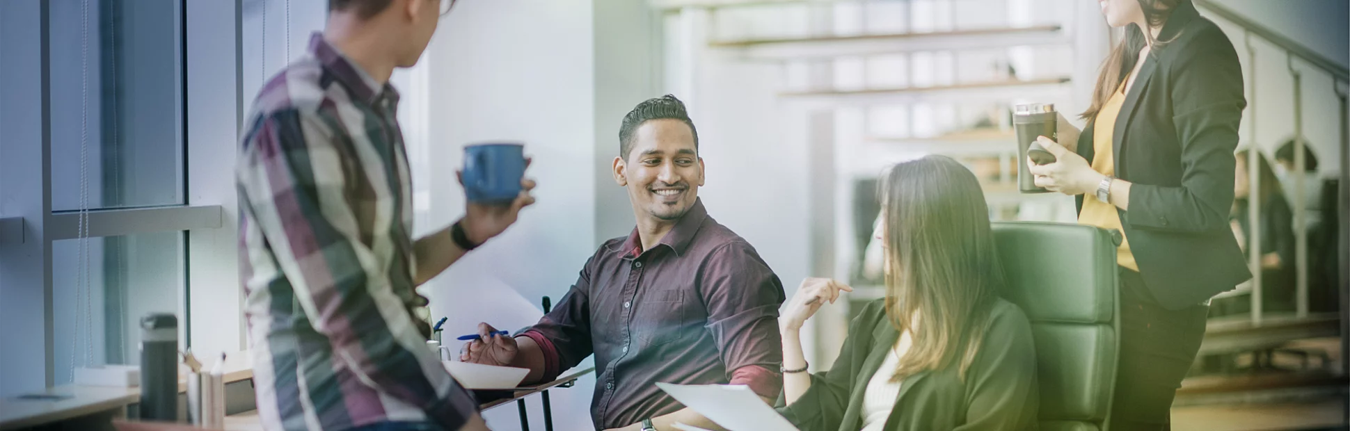 Male employee in wheelchair having cheerful discussion with colleague in an office workstation