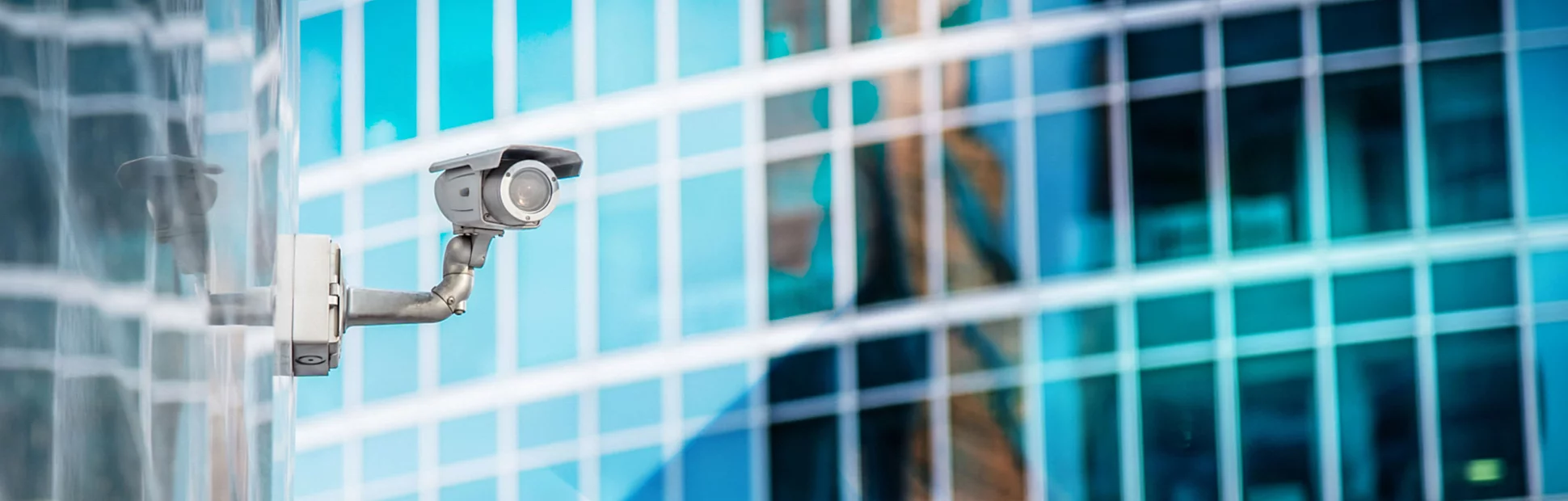 Security Camera on office building, reflecting in building behind it.