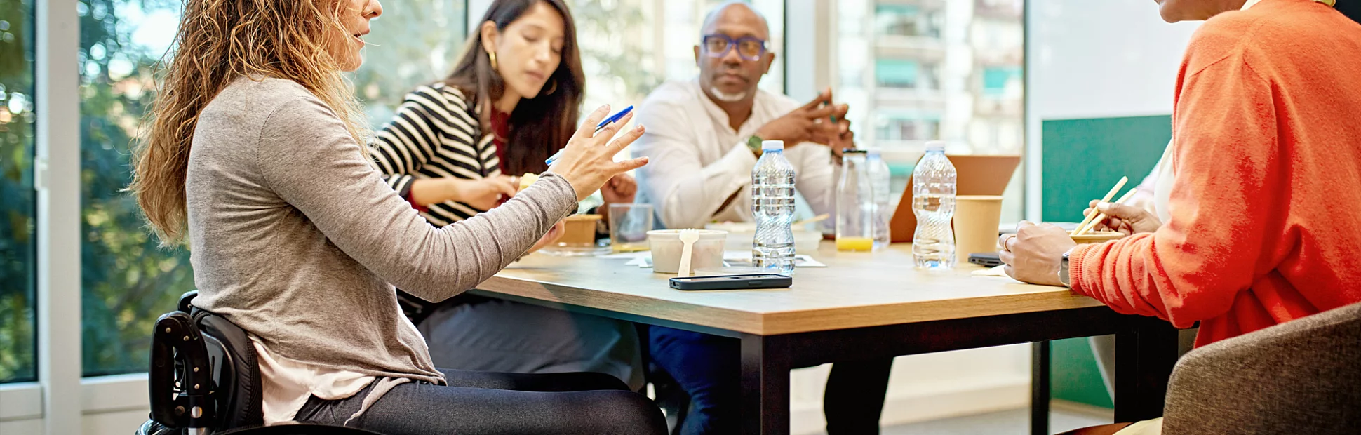 Diverse group of corporate professionals sitting around conference table conversing