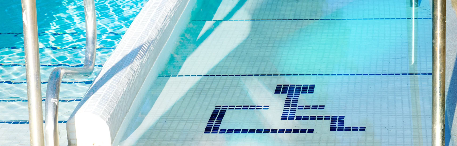 Handicap accessible ramp into a swimming pool marked with the handicapped symbol