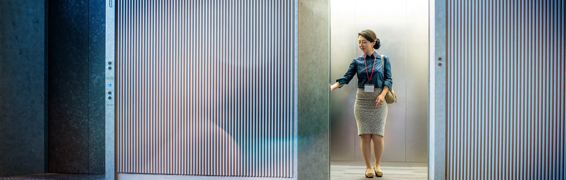 Asian businesswoman standing in elevator, waiting for doors to close.