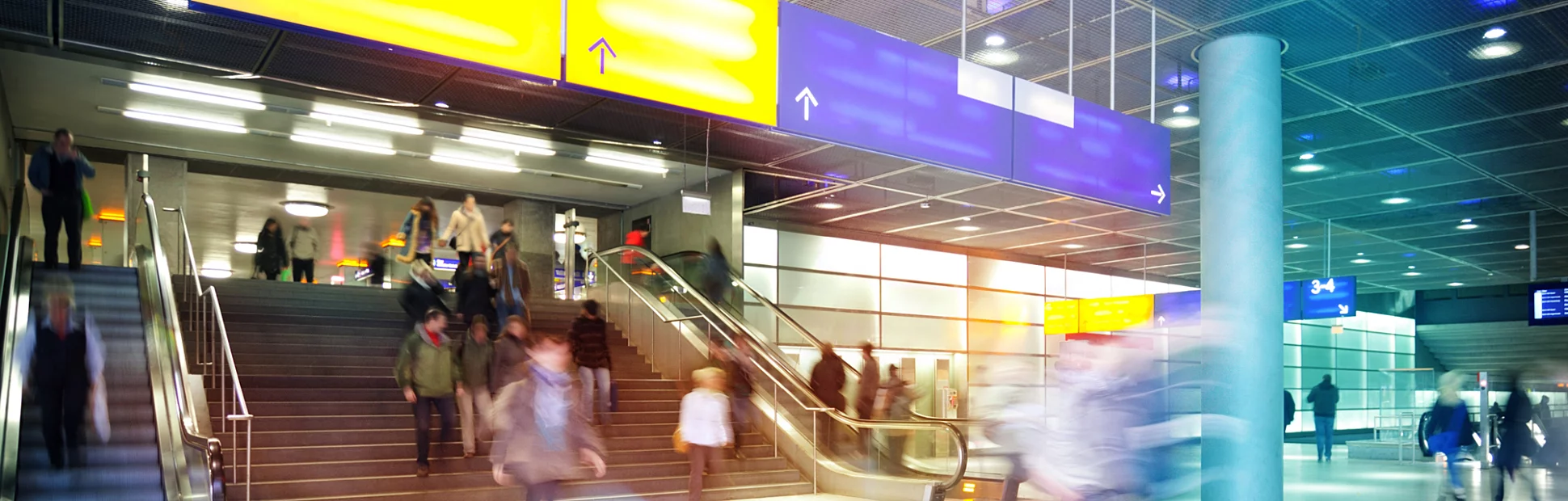Indoor image of modern train station with commuters walking to catch trains
