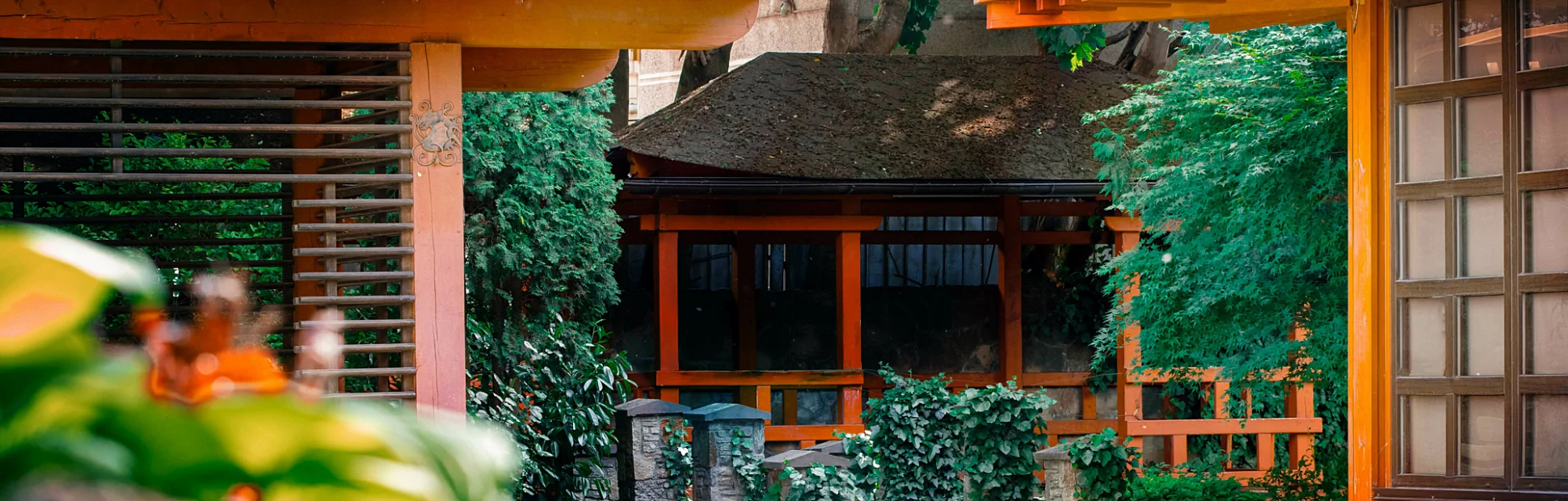 Outdoor garden at Japanese-style restaurant, landscaped design with bushes and red building