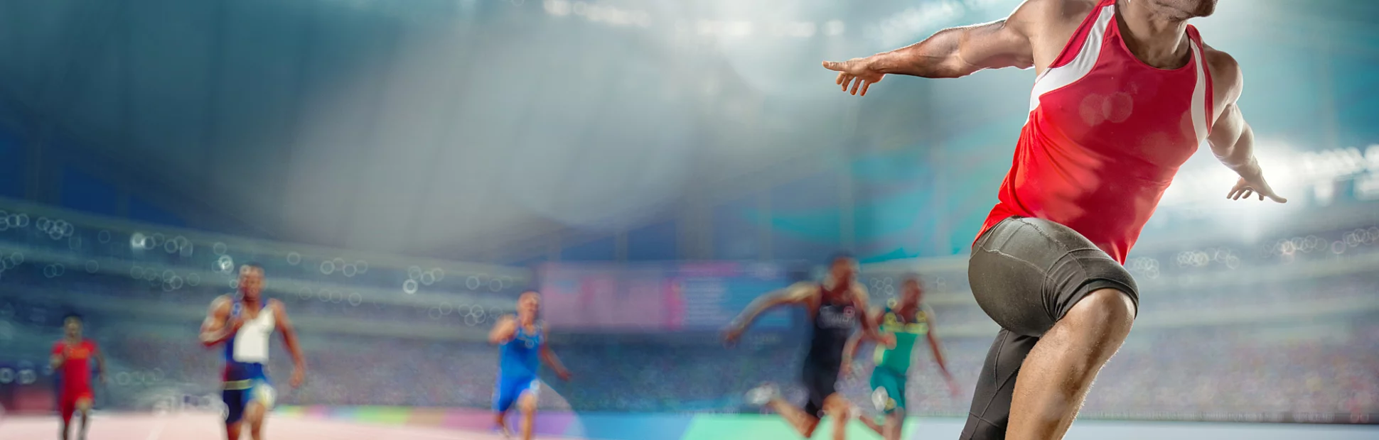 Male track athlete sprinting over the finish line of a race with his arms outstretched in victory