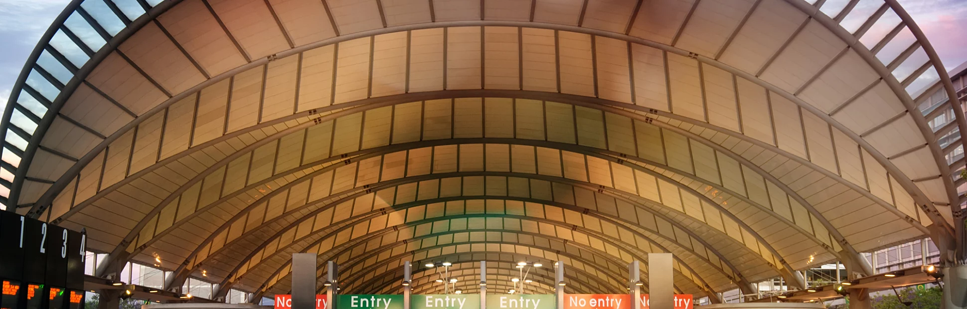The modern train station at Sydney Olympic Park, seen at dusk under a colourful sky.