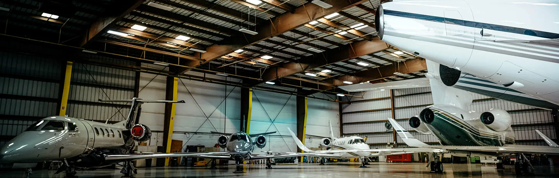Inside of a massive hangar, several aircrafts are parked.