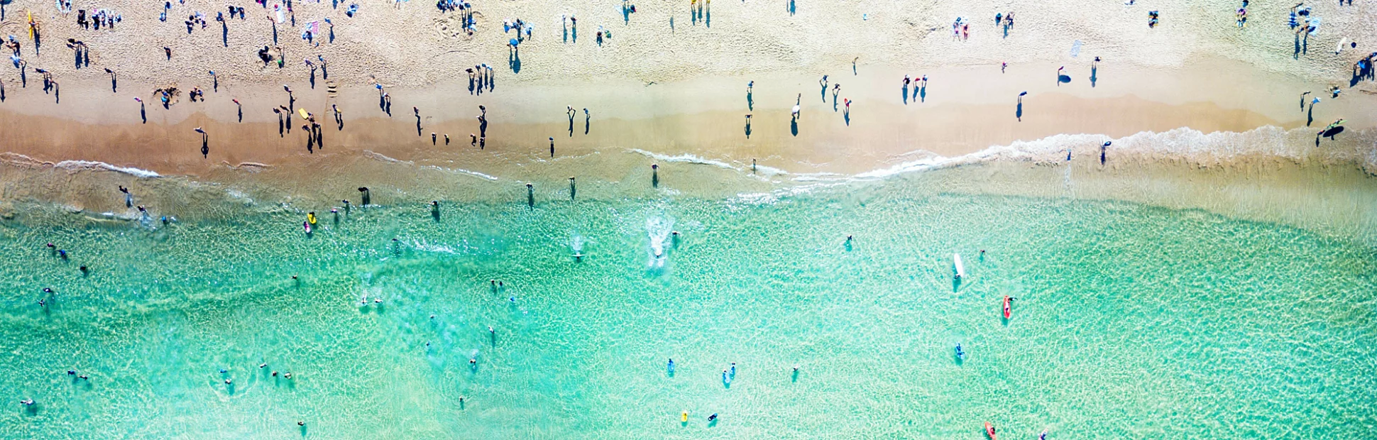 An aerial view looking down at Bondi Beach in Sydney on a busy day with blue water