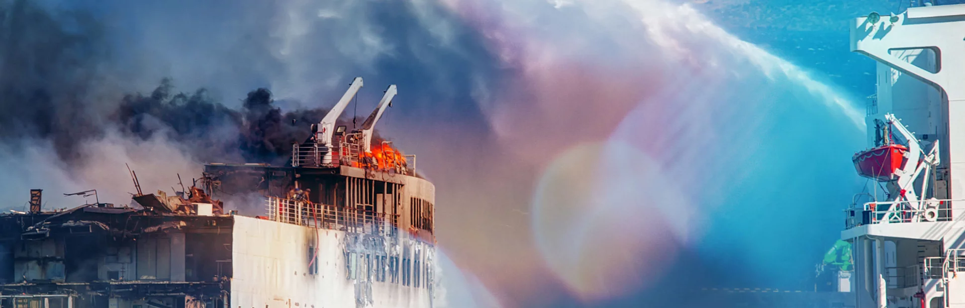 Burning ship and fire fighting boat sprays jets of water