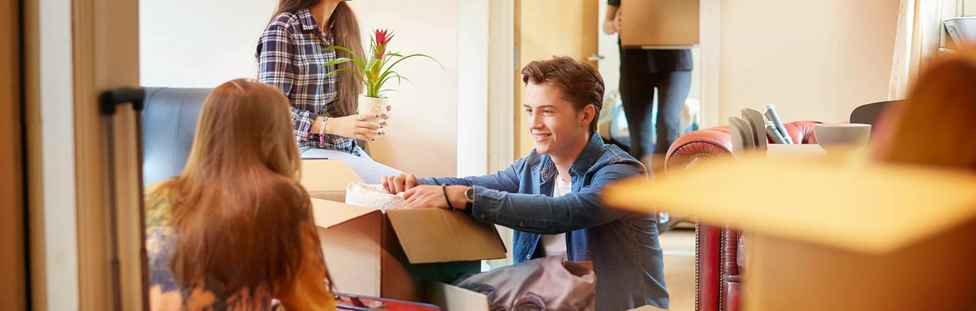 A group of four university students move into their shared flat/apartment, start to unpack boxes.
