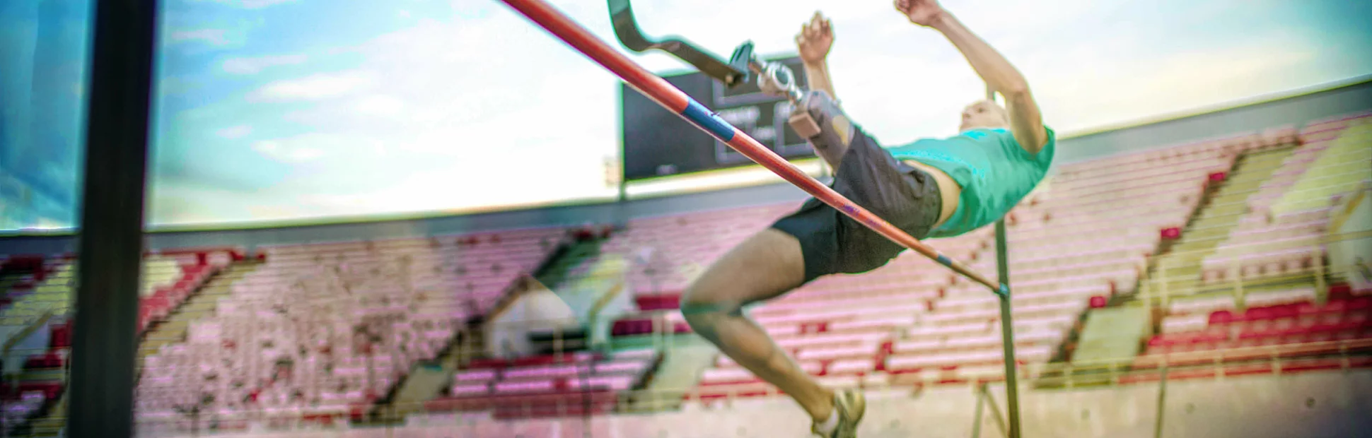 Man with a prosthetic leg jumping over a high jump bar for a track and field event