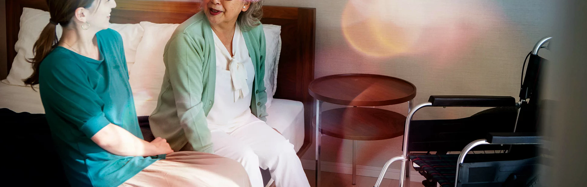 A senior woman happily chatting with her daughter on bed.