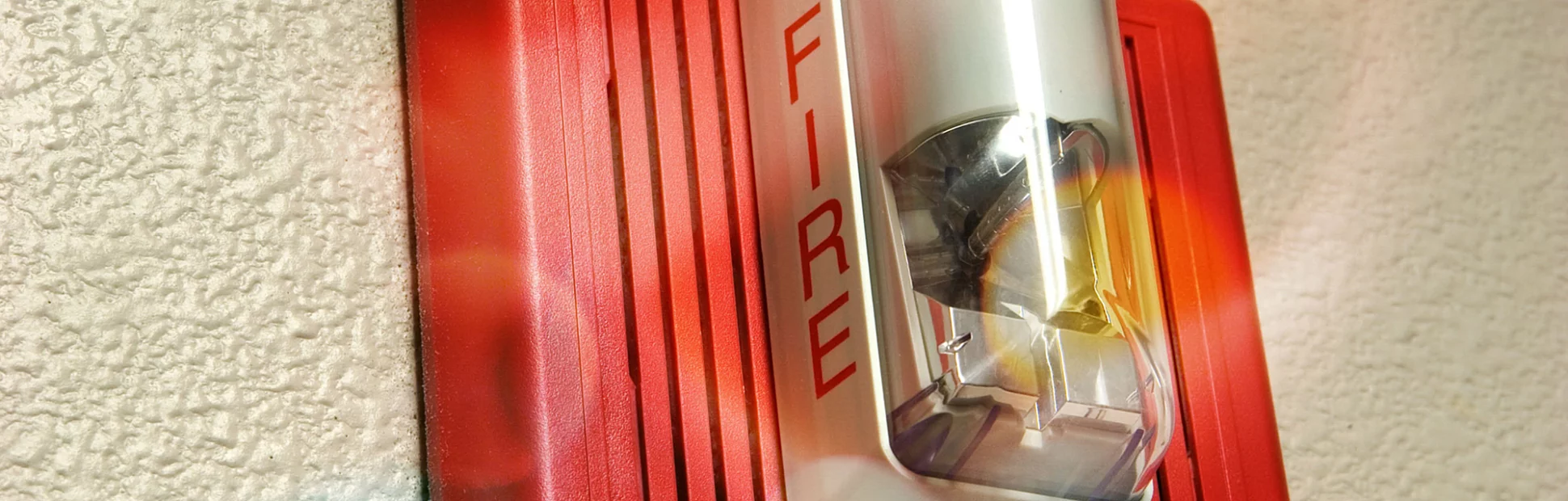 Fire alarm light and siren hanging on wall.