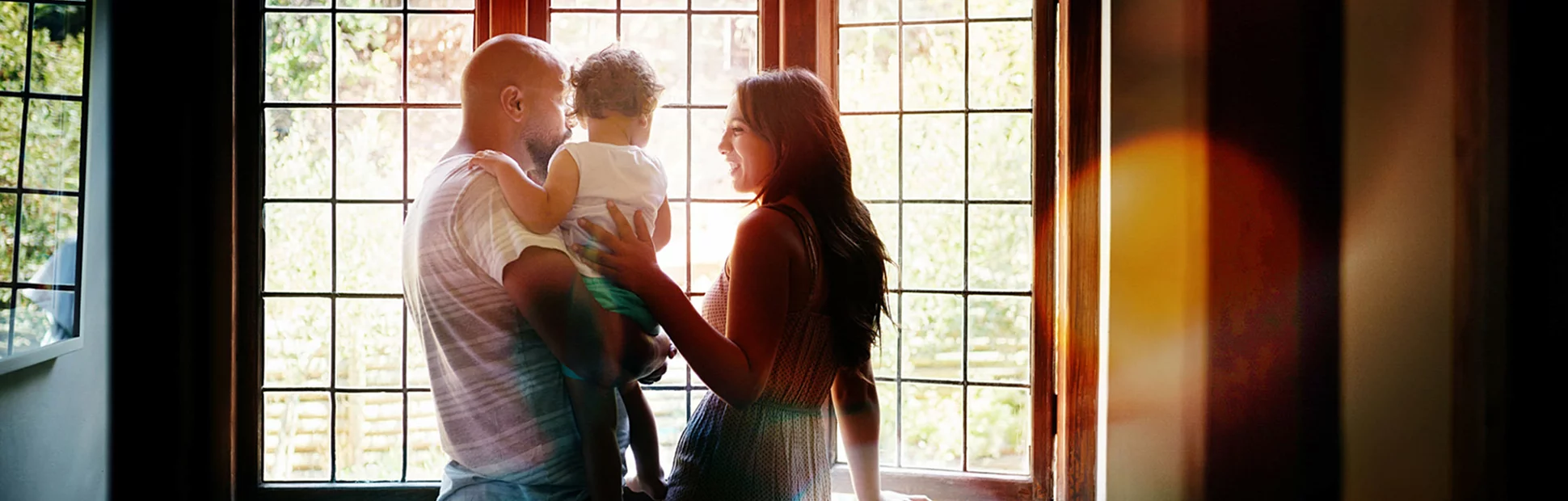 Shot of a young family looking out of the window in their new home