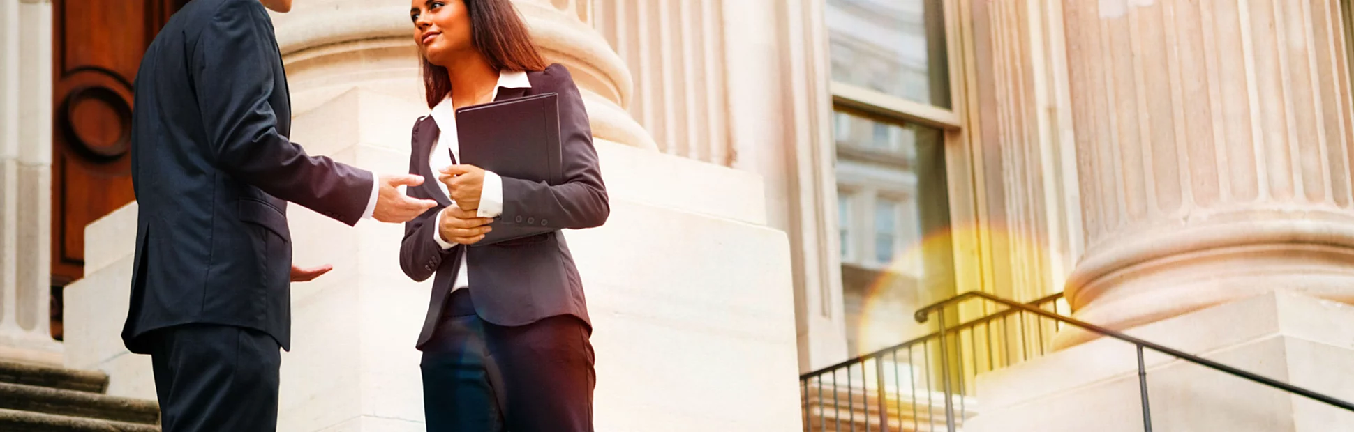 Professional woman and man having a discussion on the stairs of a stately building.