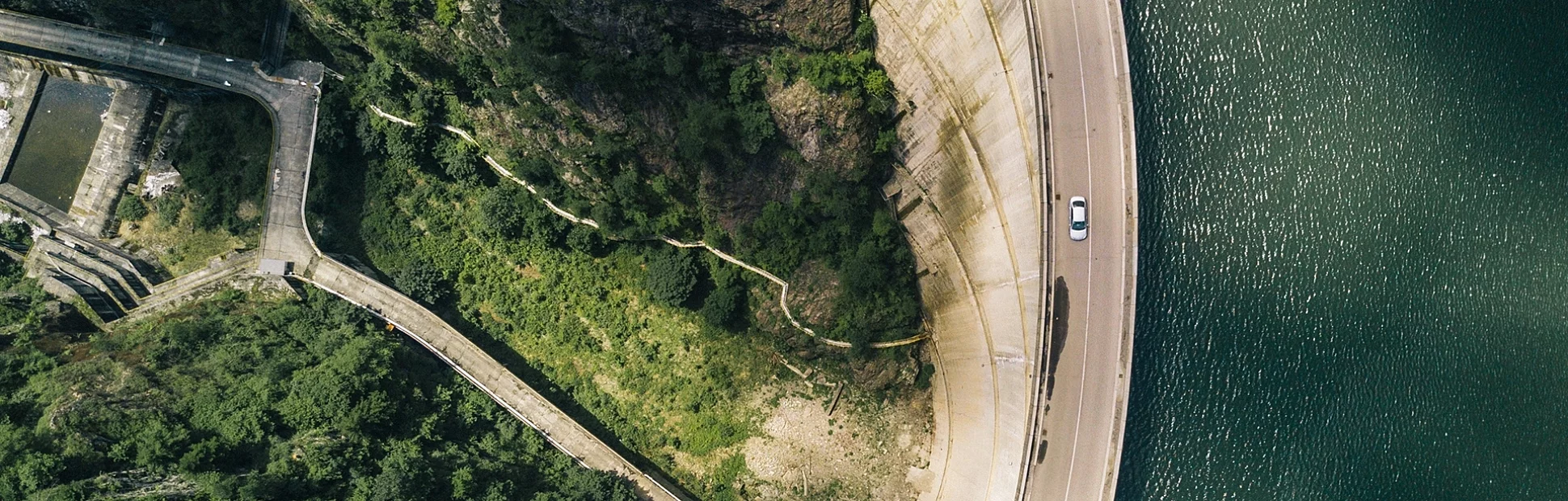 Aerial shot of a road that is next to a body of water and some foliage