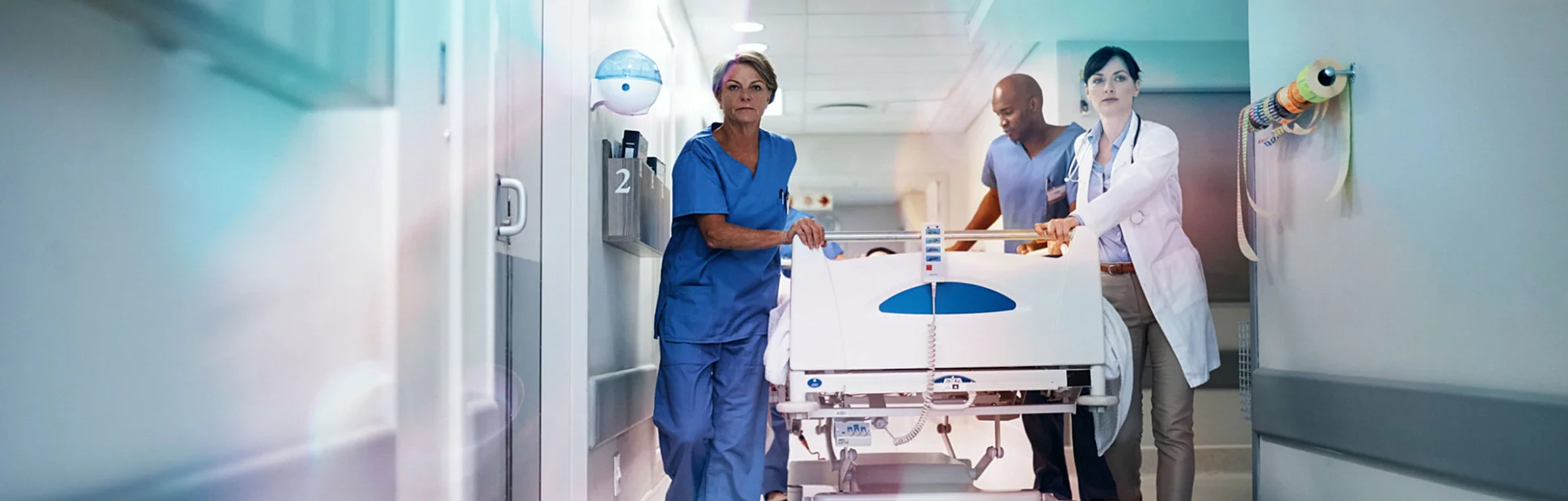 Full length shot of a medical team pushing a patient down the hallway in a gurney