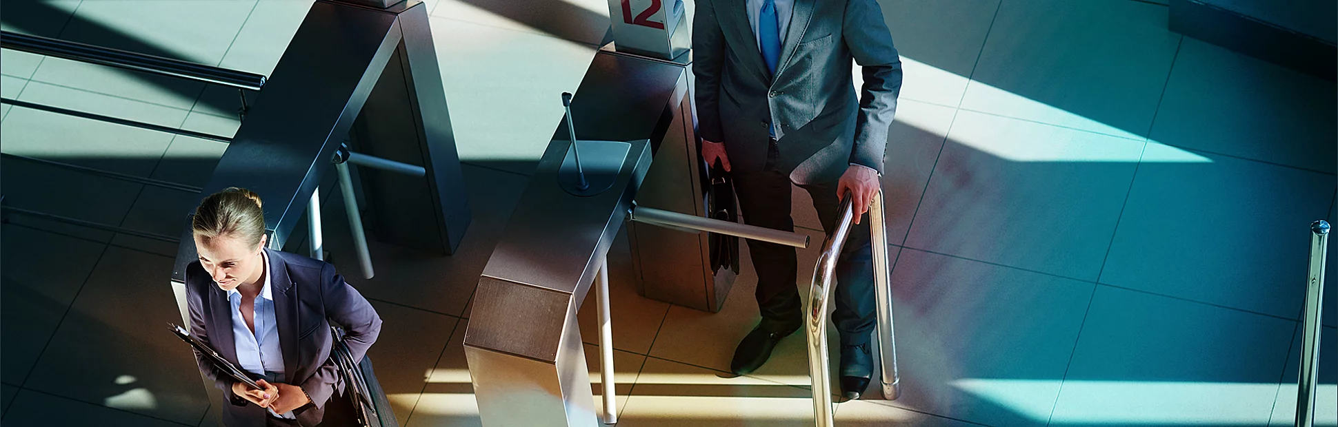 Two professional people going through a security turnstile