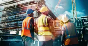 Three construction workers looking at the progress of their construction project