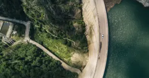 Aerial shot of a road that is next to a body of water and some foliage