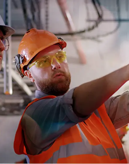 Bearded worker demonstrating fire extinguishers to mature inspector while working on power station