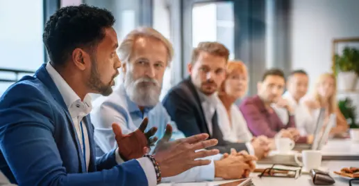 Businessman expressing opinions to colleagues on management team in conference room.