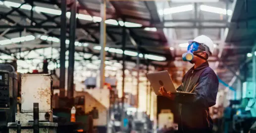 Man with protective mask and computer laptops in factory is investigating a chemical plant.