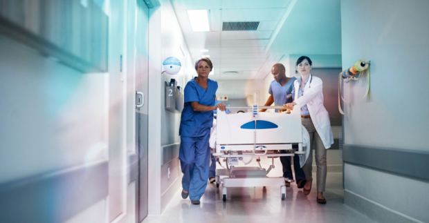 Full length shot of a medical team pushing a patient down the hallway in a gurney