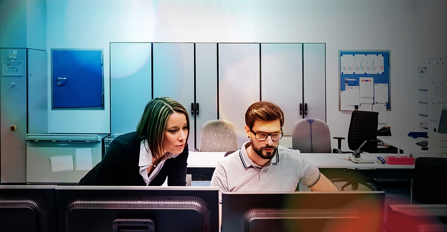 Two co workers looking at computer screens in the office