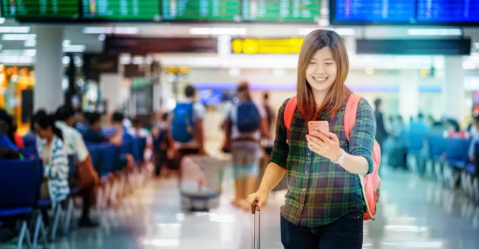 Asian traveler with luggage holding the smart mobile phone for check-in at the airport