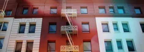 A white fire escape stands out against the red section of a building it snakes up